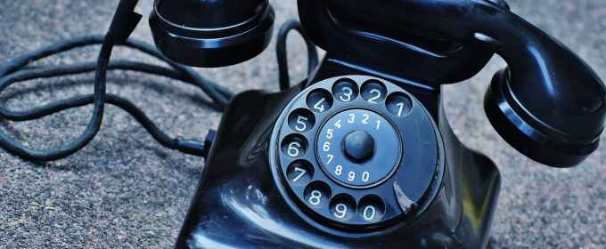 black rotary telephone at top of gray surface